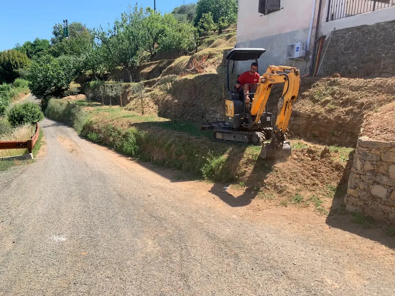Miniescavatore ADM al lavoro su un terreno vicino a un’abitazione